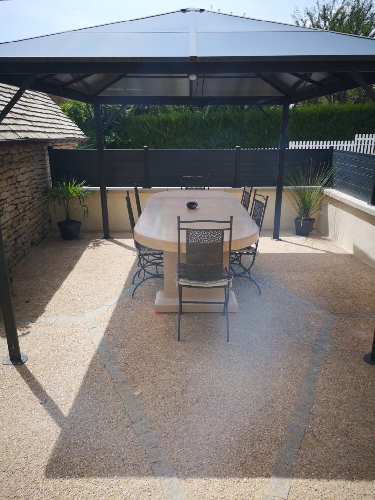 sarl-amzal - terrasse avec table au centre et pergola entouré par un muret et brise vue